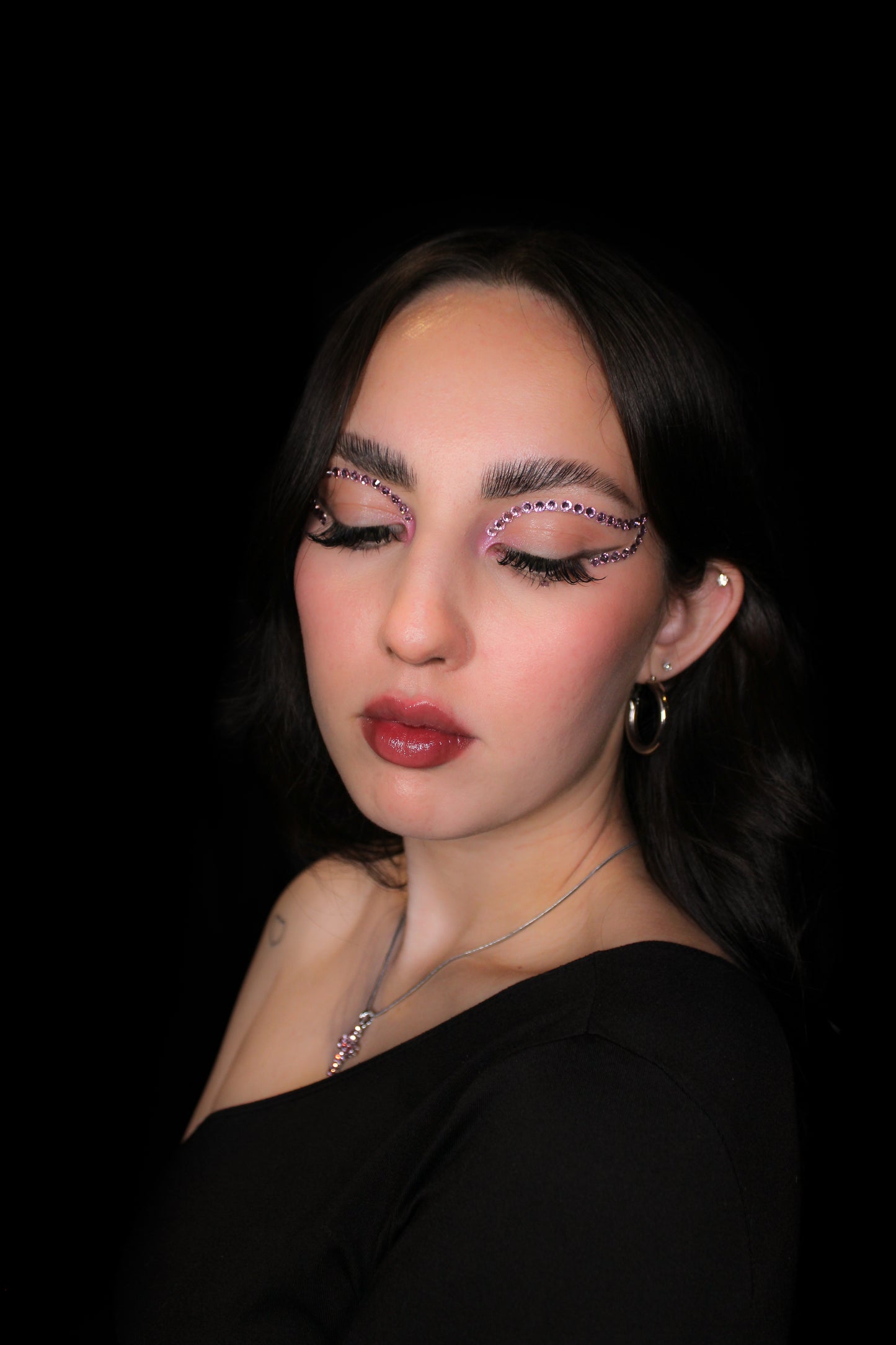 Woman with dramatic makeup and a black outfit against a dark background